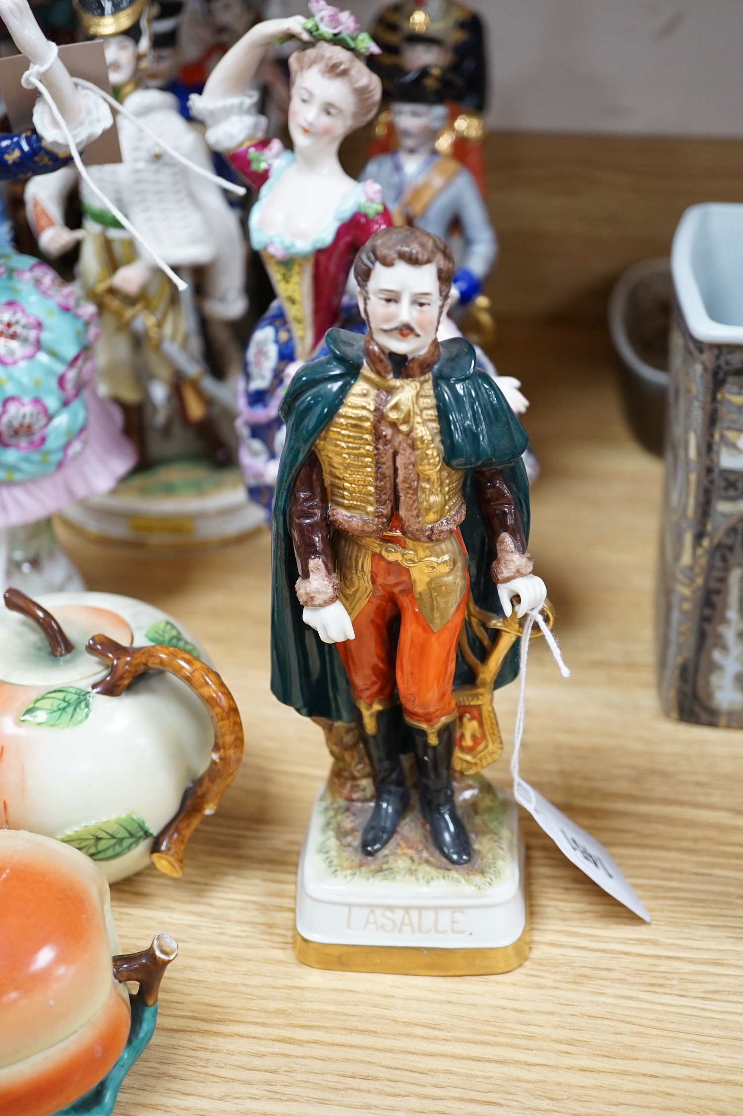 A group of Continental porcelain military figures, two porcelain figures of dancing females and four pieces of tableware in the form of fruit